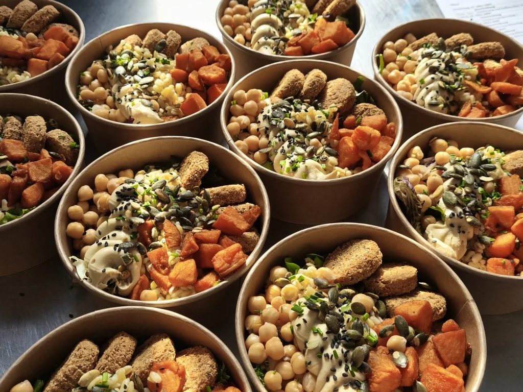 Nahaufnahme von Bowls mit Kichererbsen, Süßkartoffeln und Hummus für ein Catering-Buffet