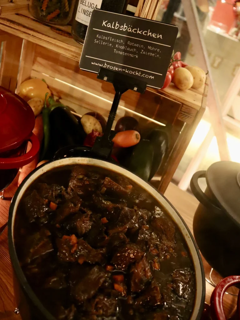 Schale mit geschmorten Kalbsbäckchen und Schild am warmen Buffet