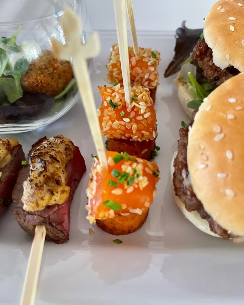 Fingerfood-Spieße und Mini-Burger auf einer weißen Catering-Platte