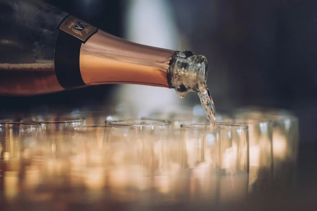 Sekt wird aus einer Flasche in eine Reihe von Gläsern eingeschenkt