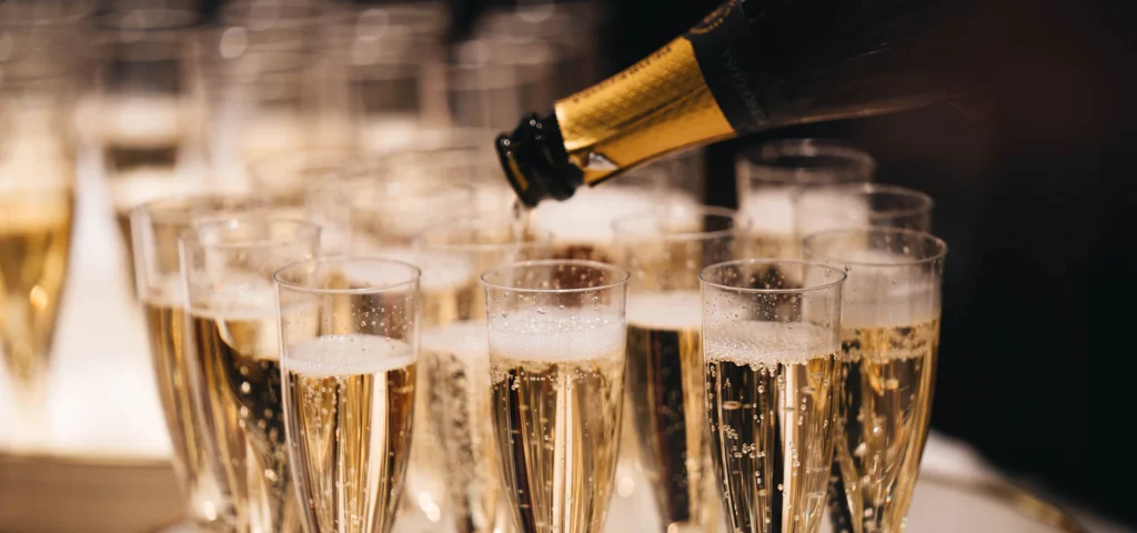 Sekt wird in bereitstehende Gläser eingeschenkt