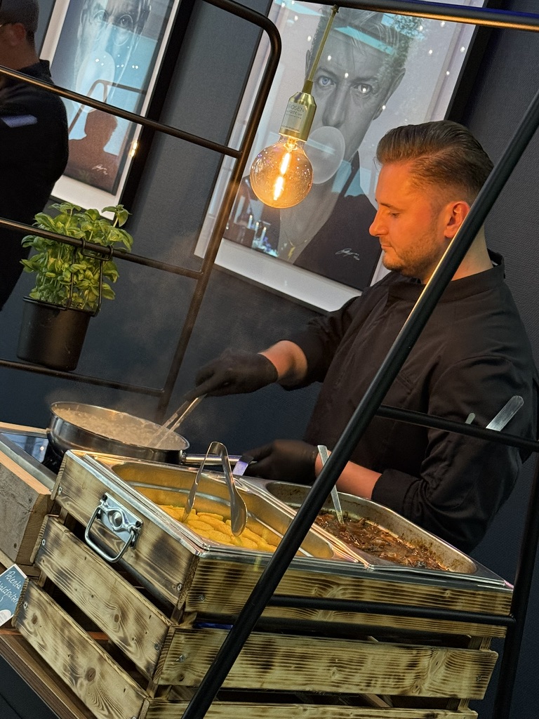 Koch bereitet an einer Live-Cooking-Station Speisen frisch zu