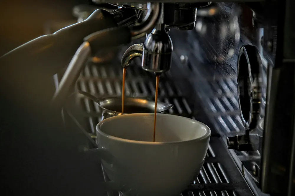 Espresso läuft aus einer Siebträgermaschine in eine weiße Tasse